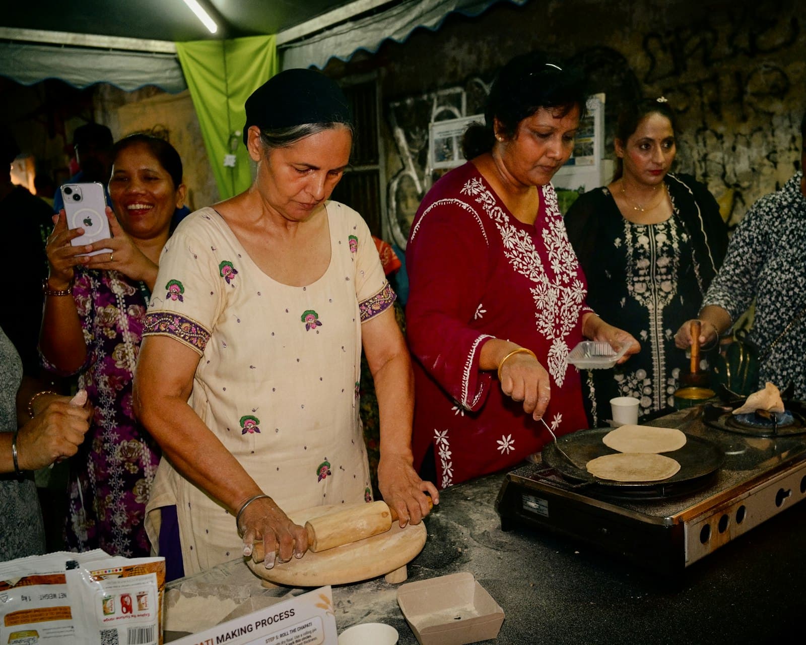 Women rolling dough and cooking flatbreads together